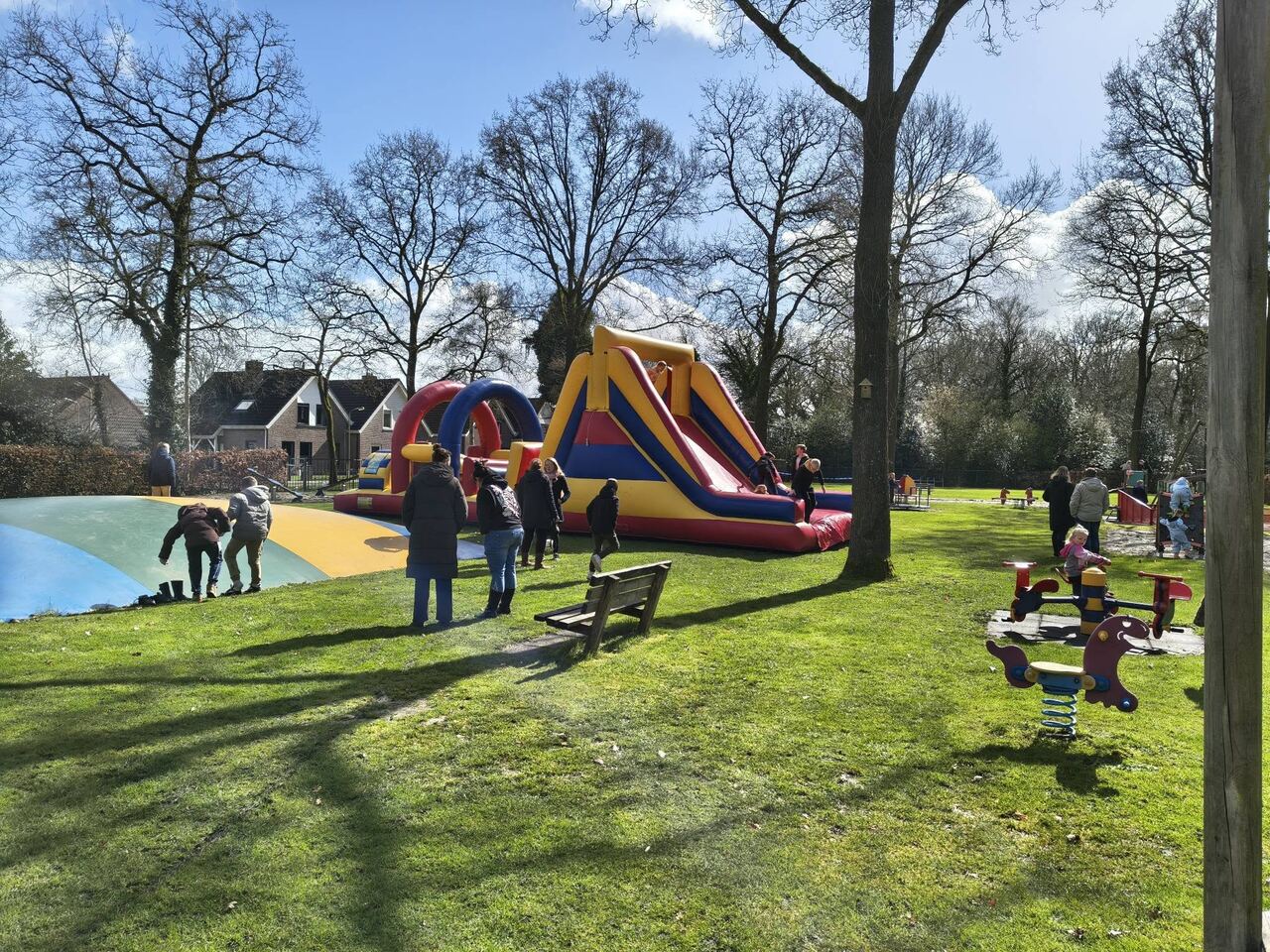 Overzicht van de speeltuin met luchtkussen, grasveld en klimtoestellen